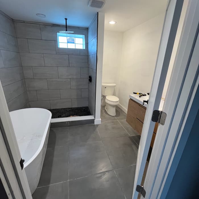 Renovated bathroom with a tiled walk-in shower and freestanding tub